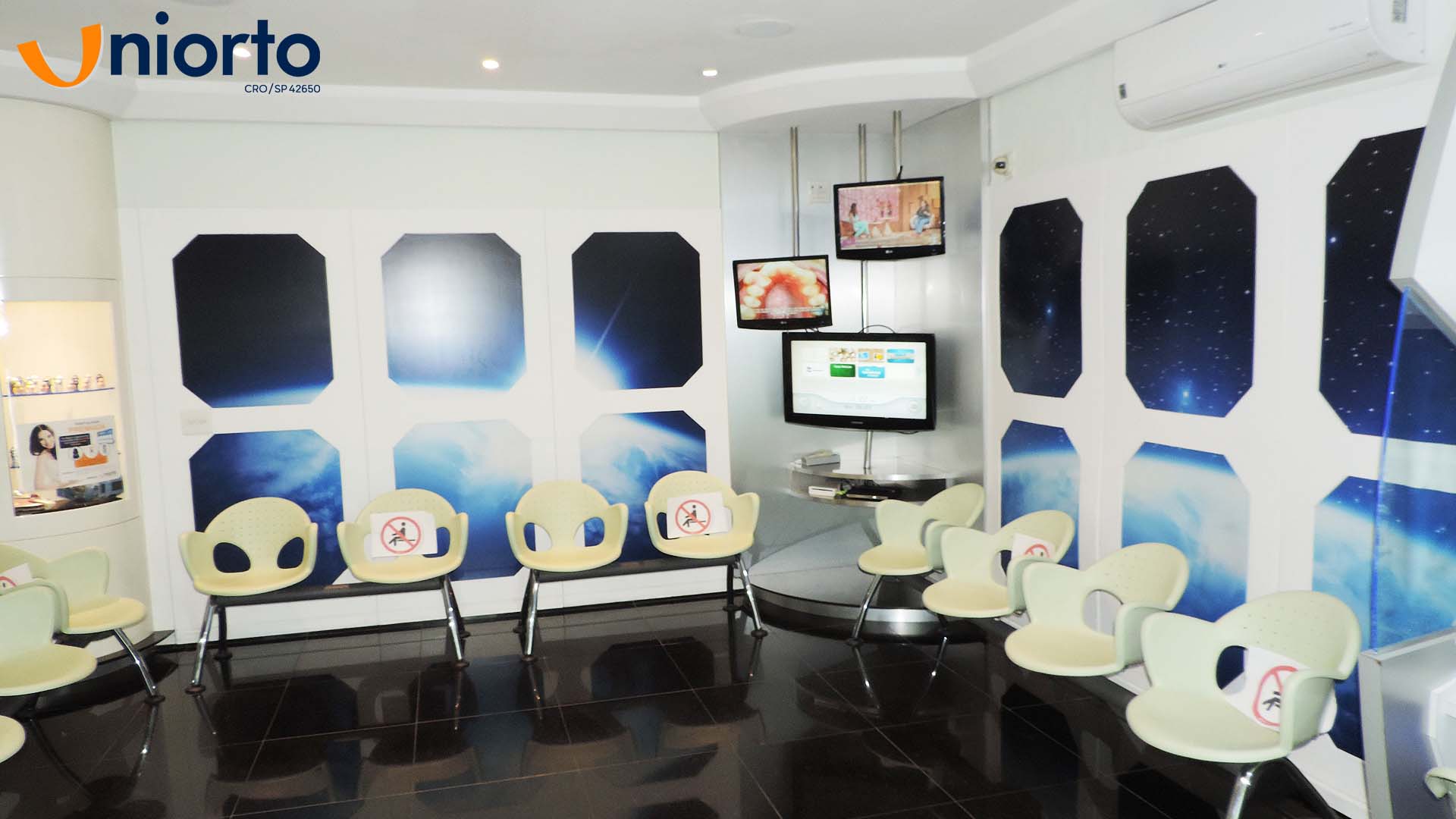 Sala de atendimento da Uniorto, com ambientação temática de galáxia nas paredes e no teto